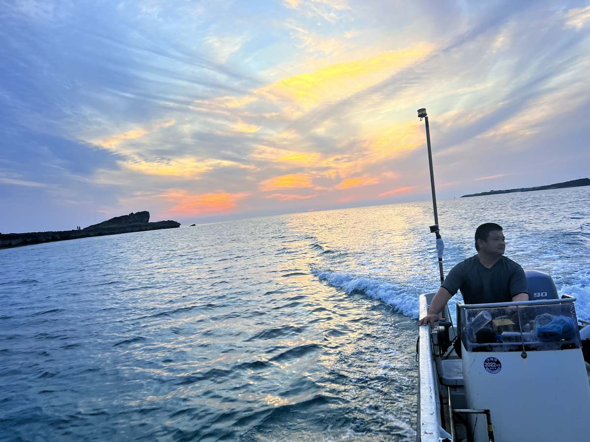 夕暮れの海を進む舟。狩俣の一日の終わり